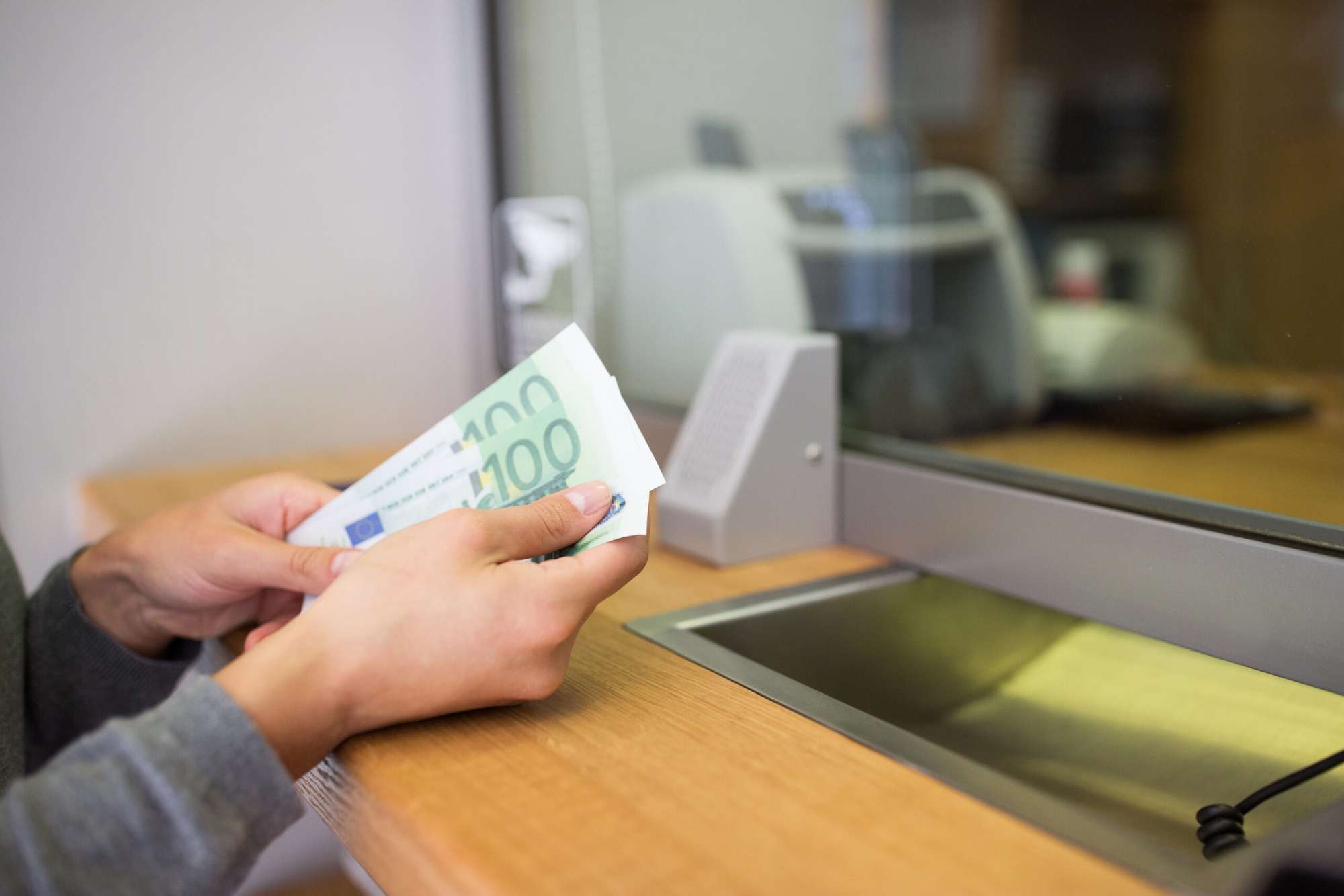Uma pessoa recebendo dinheiro em uma caixa de banco